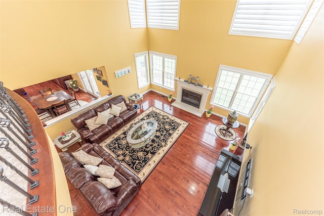 15390 Prestwick Cir, Northville, MI 48168 - living room with healthy amount of natural light, a towering ceiling, a glass covered fireplace, and wood finished floors