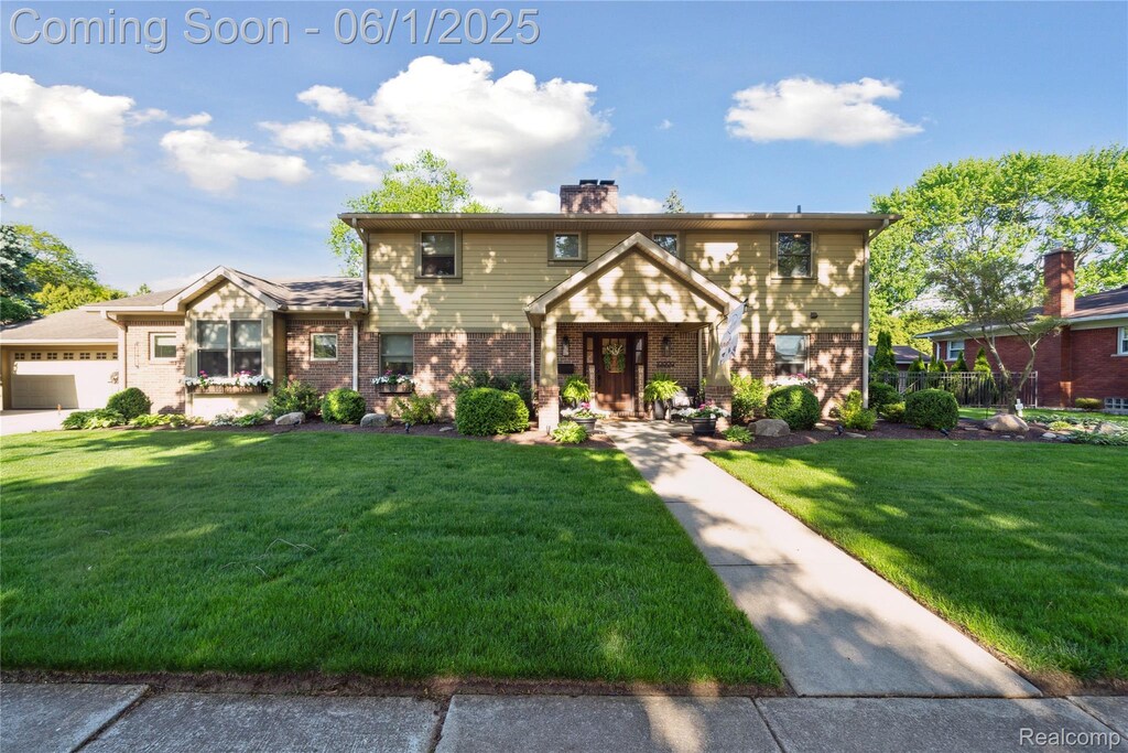 10809 Balfour Ave, Allen Park, MI 48101 - view of front of house with brick siding, a front yard, a chimney, and a garage