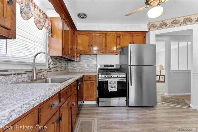 8424 Roosevelt St, Taylor, MI 48180 - kitchen featuring appliances with stainless steel finishes, brown cabinetry, light countertops, a sink, and a ceiling fan