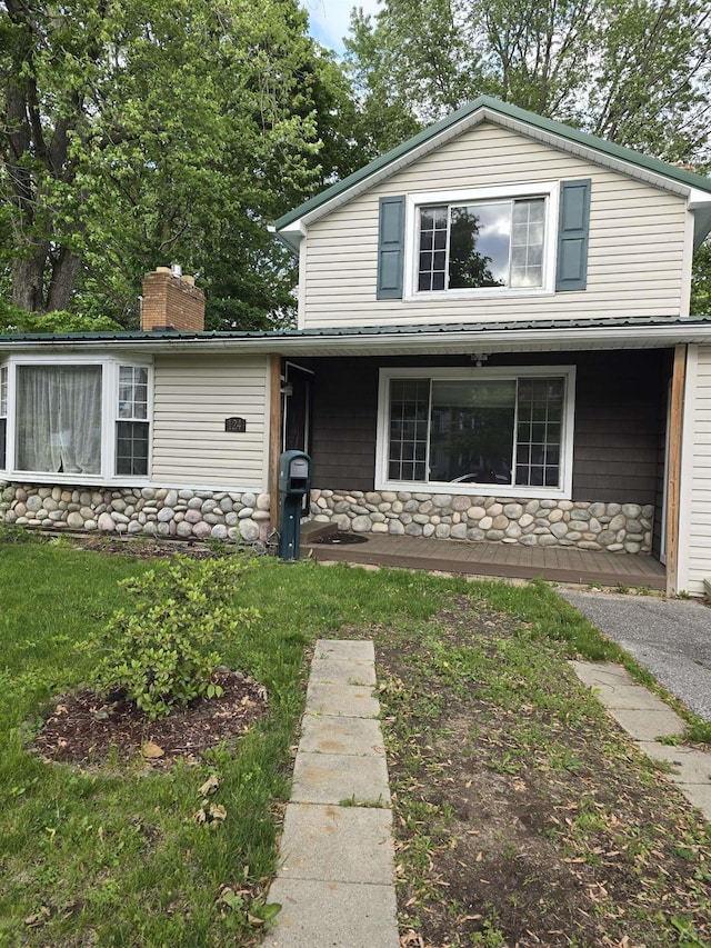 124 N Madison St, Adrian, MI 49221 - view of front of home with a porch, stone siding, a front yard, and a chimney