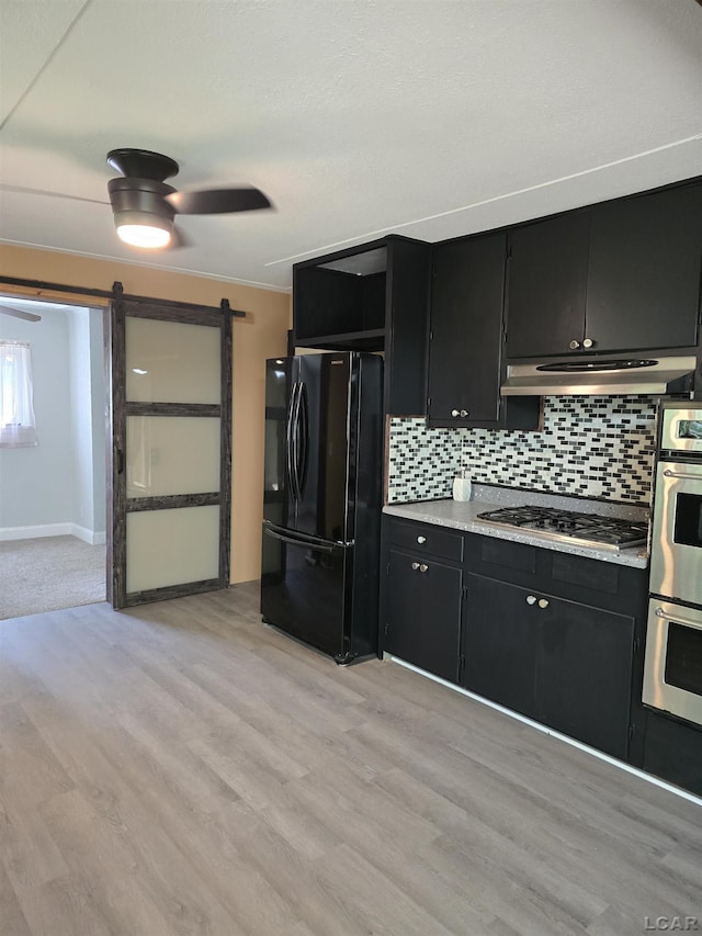 124 N Madison St, Adrian, MI 49221 - kitchen featuring appliances with stainless steel finishes, dark cabinets, a barn door, and tasteful backsplash