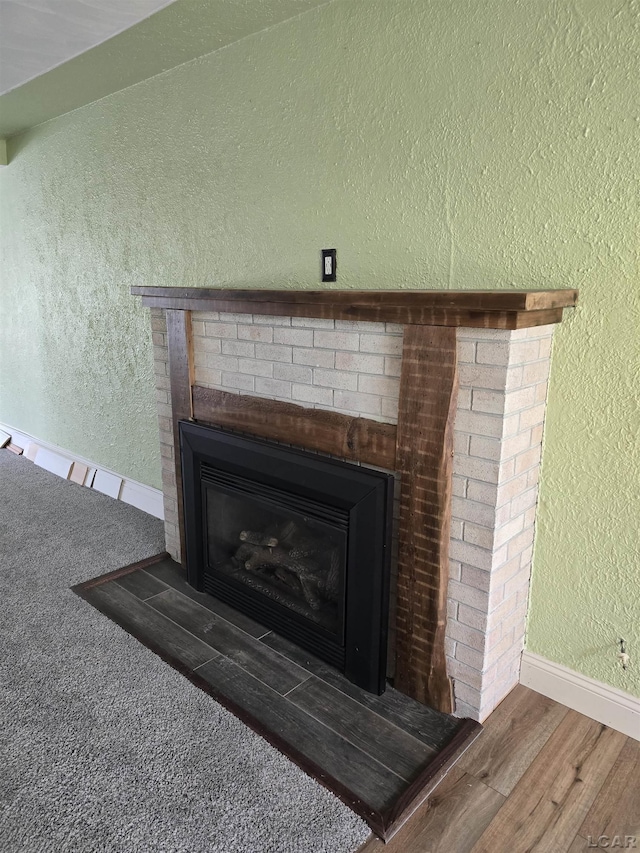 124 N Madison St, Adrian, MI 49221 - detailed view of a fireplace, a textured wall, and wood finished floors