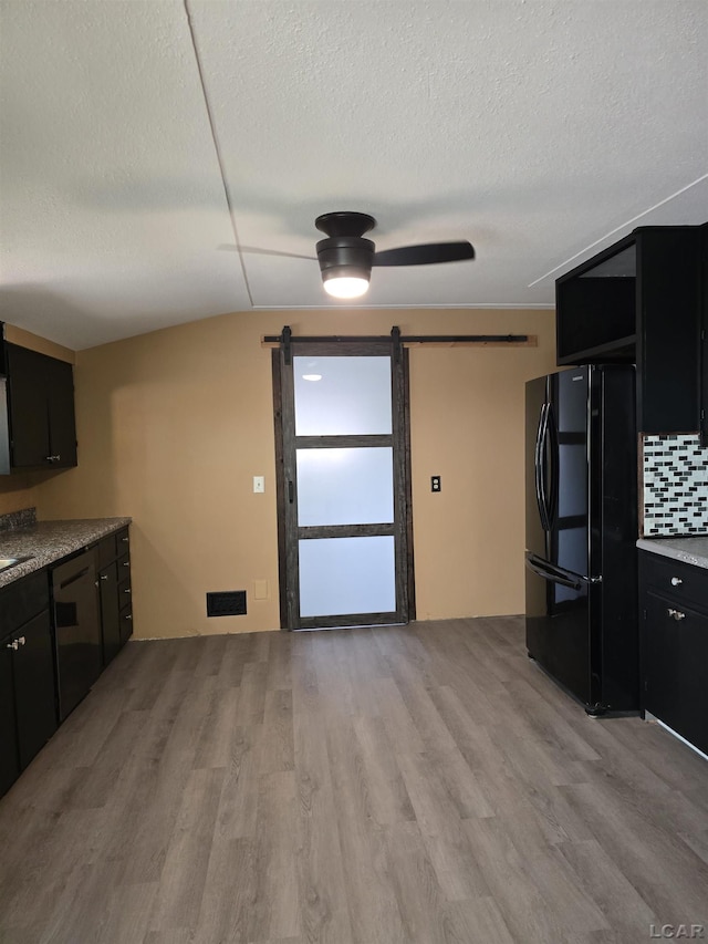 124 N Madison St, Adrian, MI 49221 - kitchen featuring black appliances, a barn door, dark cabinets, light wood-style flooring, and a textured ceiling