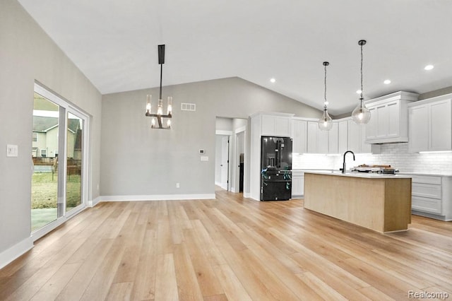 7195 Geraldine Cir, Swartz Creek, MI 48473 - kitchen with black fridge with ice dispenser, light countertops, decorative backsplash, a chandelier, and light wood-type flooring