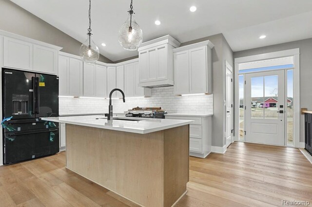 7195 Geraldine Cir, Swartz Creek, MI 48473 - kitchen with black refrigerator with ice dispenser, a sink, decorative backsplash, light countertops, and light wood-type flooring