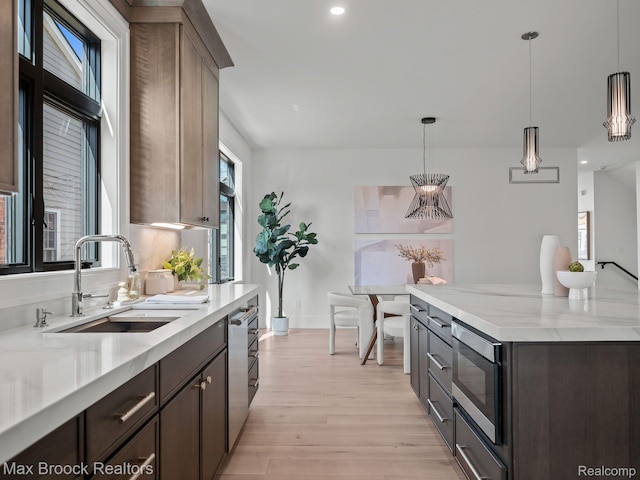 667 Oak Ave, Birmingham, MI 48009 - kitchen featuring a sink, stainless steel appliances, light wood-style flooring, hanging light fixtures, and baseboards