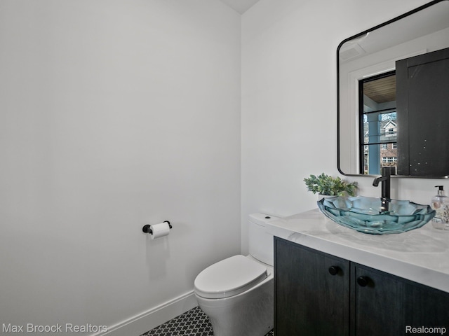 667 Oak Ave, Birmingham, MI 48009 - half bathroom with vanity, toilet, baseboards, and tile patterned flooring