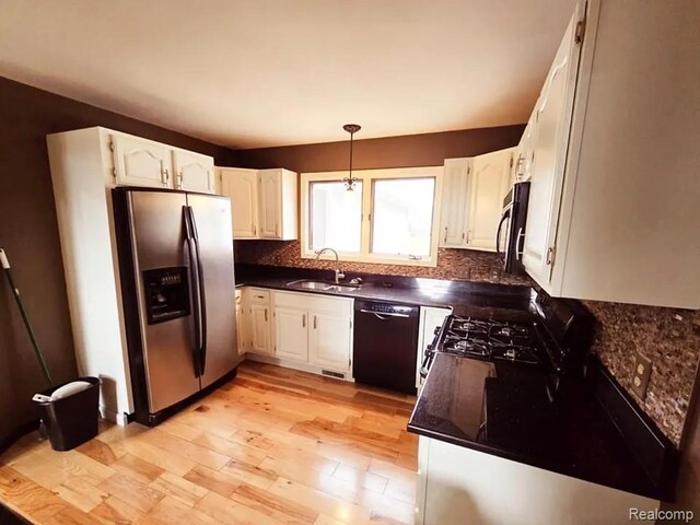 9418 Rayna Dr Unit 62, Davison, MI 48423 - kitchen with black dishwasher, stainless steel fridge with ice dispenser, a sink, dark countertops, and light wood finished floors