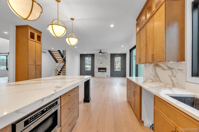 4627 Cimarron Dr, Bloomfield Hills, MI 48302 - kitchen featuring a large fireplace, recessed lighting, light wood-type flooring, pendant lighting, and glass insert cabinets