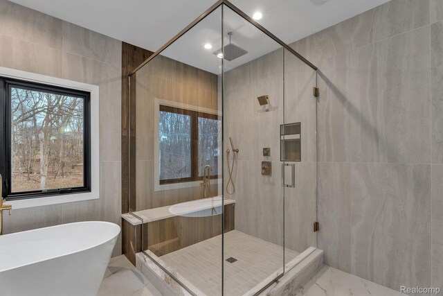 4627 Cimarron Dr, Bloomfield Hills, MI 48302 - bathroom with marble look tiles, a freestanding bath, a shower stall, healthy amount of natural light, and tile walls