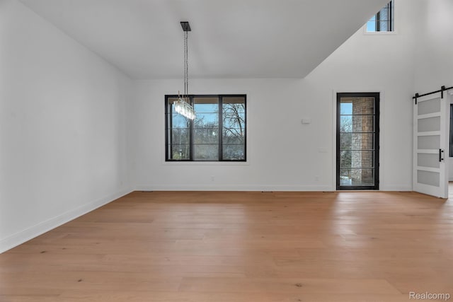 4627 Cimarron Dr, Bloomfield Hills, MI 48302 - unfurnished dining area featuring plenty of natural light, a barn door, light wood-style floors, and a high ceiling
