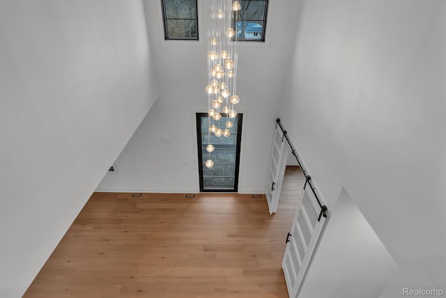 4627 Cimarron Dr, Bloomfield Hills, MI 48302 - entryway featuring light wood-style floors, a chandelier, baseboards, a high ceiling, and a barn door