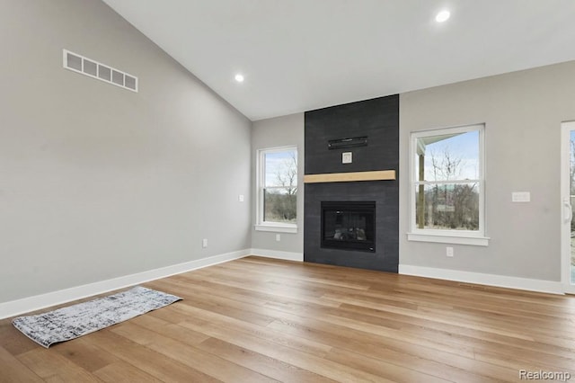 11302 Princewood Cir, Fenton, MI 48430 - unfurnished living room with light wood-style flooring, baseboards, healthy amount of natural light, vaulted ceiling, and a large fireplace
