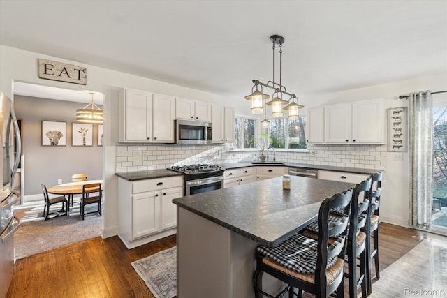177 Summer Shade Dr, Howell, MI 48843 - kitchen featuring appliances with stainless steel finishes, a kitchen breakfast bar, dark countertops, and a sink