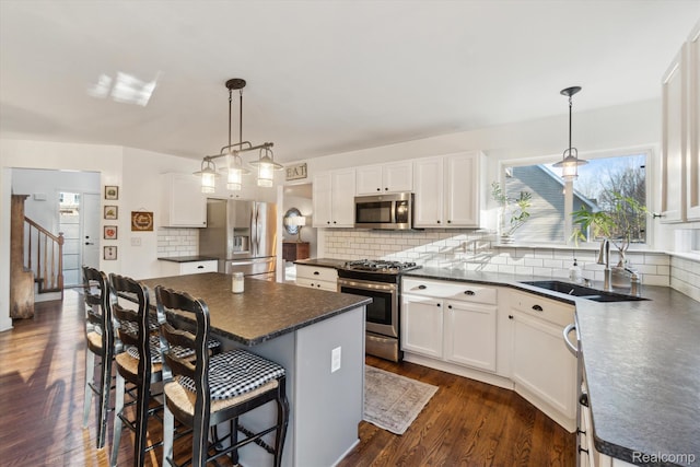 177 Summer Shade Dr, Howell, MI 48843 - kitchen featuring appliances with stainless steel finishes, dark countertops, a sink, a kitchen island, and backsplash