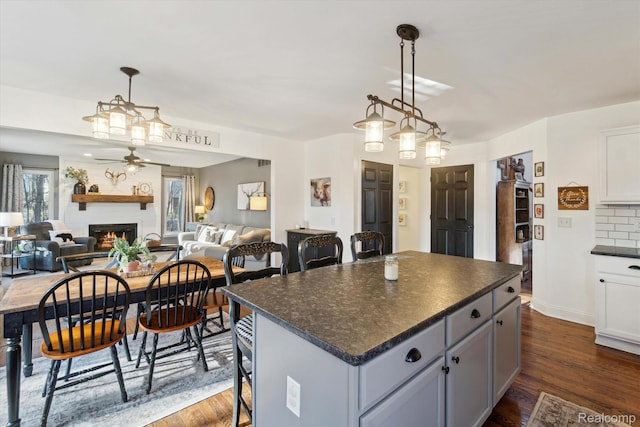 177 Summer Shade Dr, Howell, MI 48843 - kitchen featuring ceiling fan, dark countertops, a large fireplace, open floor plan, and dark wood-style floors