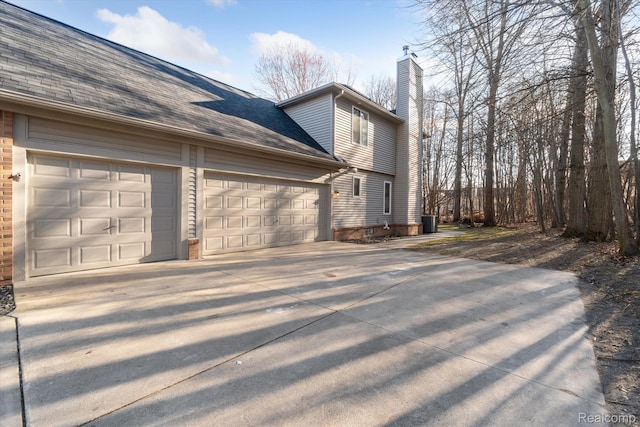 177 Summer Shade Dr, Howell, MI 48843 - view of property exterior featuring a chimney, concrete driveway, a garage, brick siding, and roof with shingles