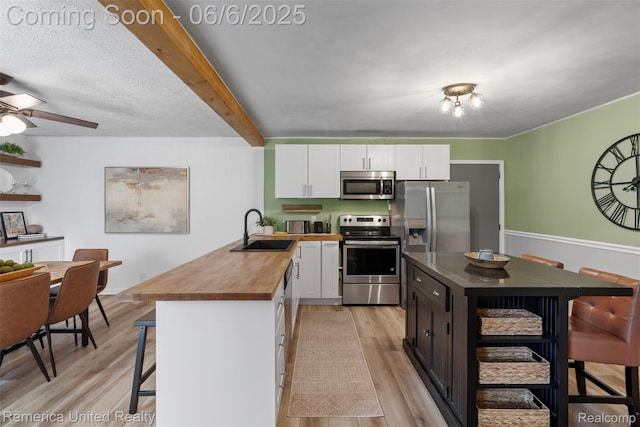 569 Lyon Blvd, South Lyon, MI 48178 - kitchen featuring stainless steel appliances, a sink, wood counters, a kitchen breakfast bar, and light wood-type flooring