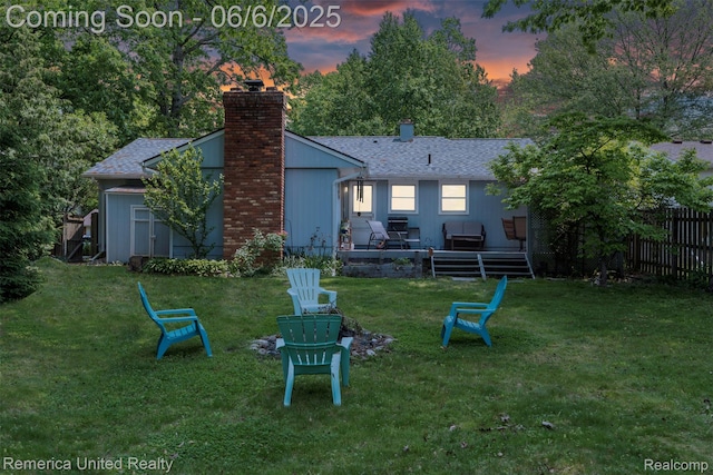 569 Lyon Blvd, South Lyon, MI 48178 - back of house at dusk with a chimney, a shingled roof, and an outdoor fire pit