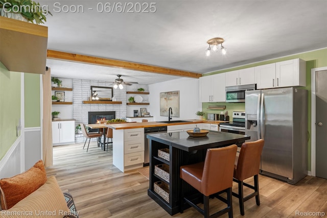 569 Lyon Blvd, South Lyon, MI 48178 - kitchen with stainless steel appliances, open floor plan, a peninsula, white cabinetry, and beamed ceiling