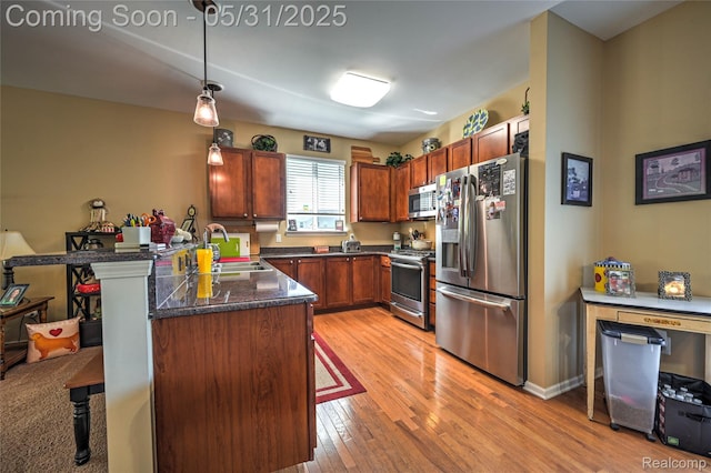 28329 Cottage Ln, New Hudson, MI 48165 - kitchen with stainless steel appliances, a sink, a kitchen breakfast bar, light wood-style floors, and pendant lighting