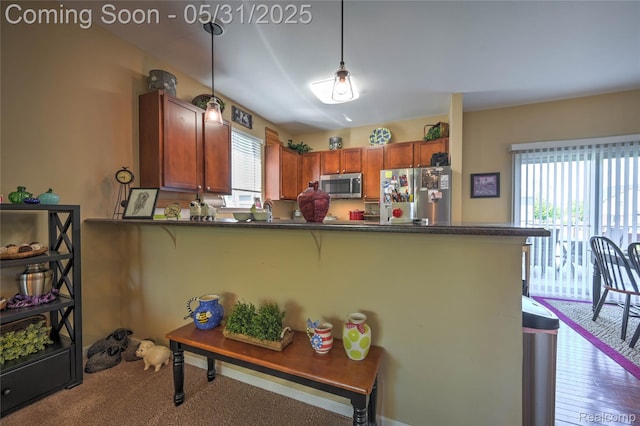 28329 Cottage Ln, New Hudson, MI 48165 - kitchen with stainless steel appliances, dark countertops, a breakfast bar area, a peninsula, and hanging light fixtures