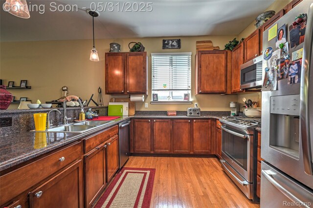 28329 Cottage Ln, New Hudson, MI 48165 - kitchen with stainless steel appliances, a sink, light wood-type flooring, pendant lighting, and dark stone counters