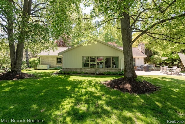 1816 Ledbury Dr, Bloomfield Hills, MI 48304 - rear view of house with brick siding, a patio area, a lawn, and a chimney