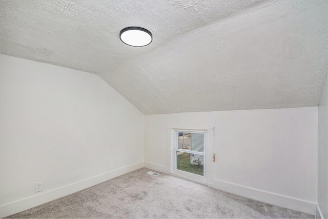 723 Baxter St SE, Grand Rapids, MI 49503 - additional living space featuring a textured ceiling, lofted ceiling, baseboards, and light carpet