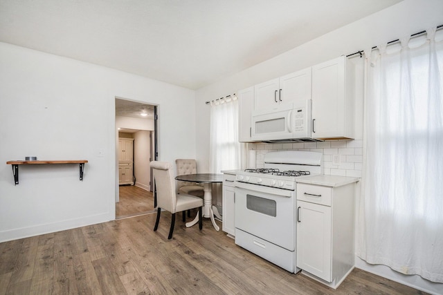 723 Baxter St SE, Grand Rapids, MI 49503 - kitchen with white appliances, decorative backsplash, light wood-style floors, white cabinetry, and light countertops