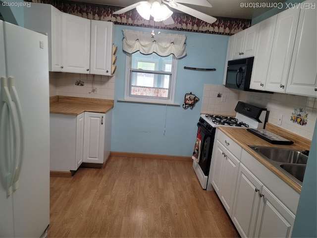 29751 Balmoral St, Garden City, MI 48135 - kitchen featuring freestanding refrigerator, range with gas stovetop, black microwave, light wood-type flooring, and white cabinetry