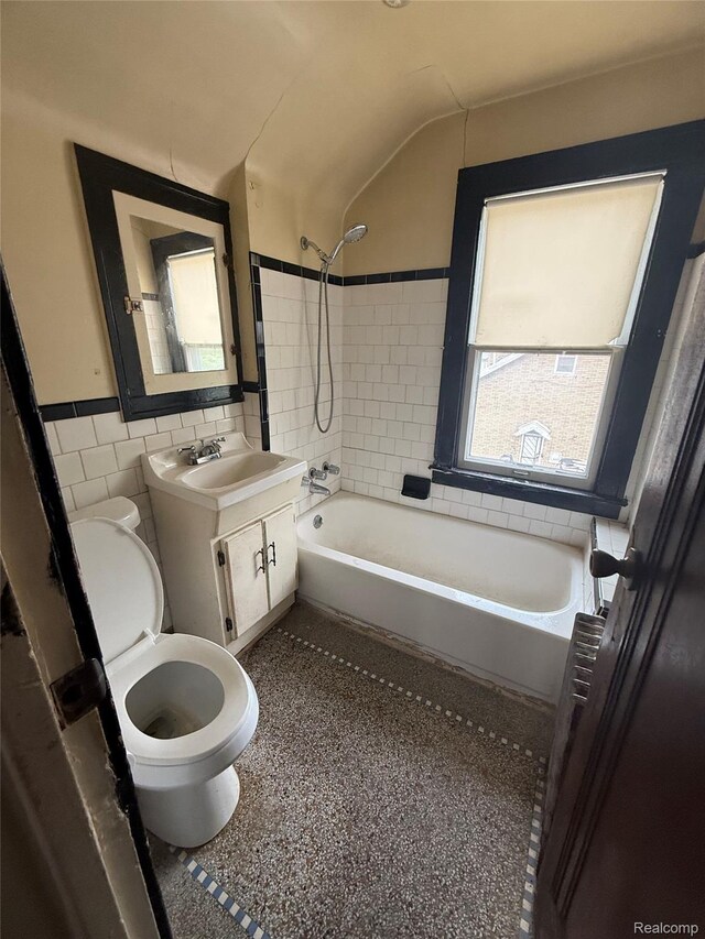 8071 Elgin St, Detroit, MI 48234 - bathroom featuring tile walls, toilet, shower / bathtub combination, vanity, and a wainscoted wall