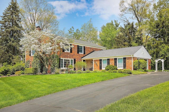 647 S Spinningwheel Ln, Michigan, MI 48304 - colonial inspired home with a chimney, brick siding, and a front yard