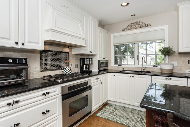 647 S Spinningwheel Ln, Michigan, MI 48304 - kitchen with stainless steel appliances, a sink, white cabinets, backsplash, and dark stone countertops