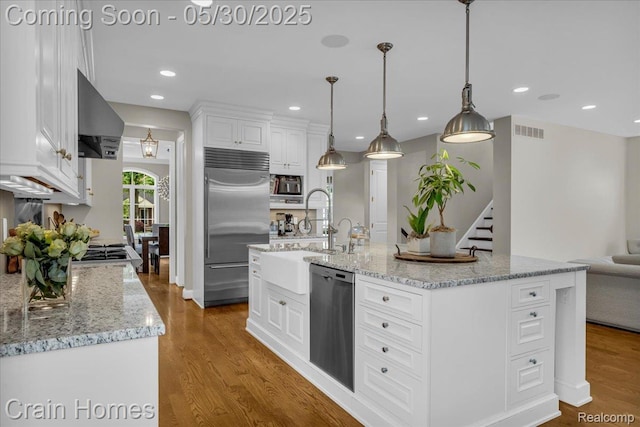 499 Catalpa Dr, Birmingham, MI 48009 - kitchen featuring built in appliances, white cabinets, wood finished floors, wall chimney exhaust hood, and a sink
