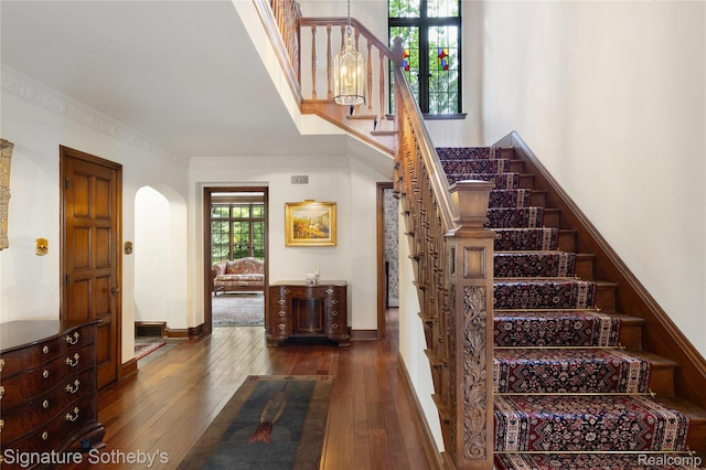 401 Dunston Rd, Bloomfield Hills, MI 48304 - staircase with hardwood / wood-style floors, arched walkways, crown molding, a high ceiling, and baseboards