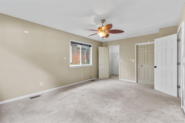 1914 10th St, Port Huron, MI 48060 - unfurnished bedroom featuring baseboards, light carpet, ceiling fan, a spacious closet, and a textured ceiling