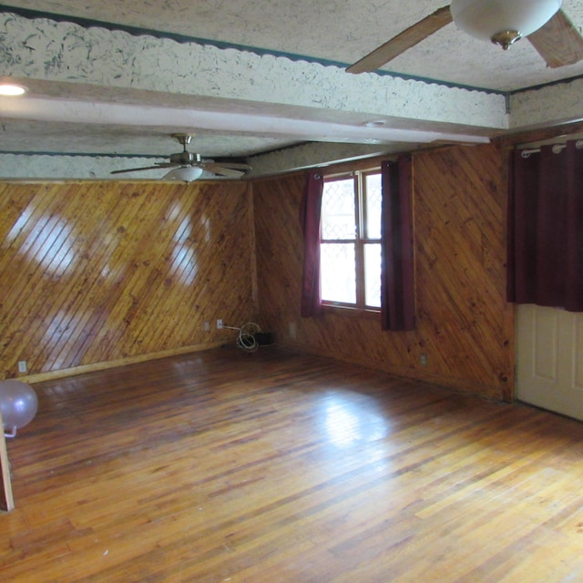 814 Ira Ave, Kalamazoo, MI 49048 - empty room with ceiling fan, wood walls, beam ceiling, and wood finished floors