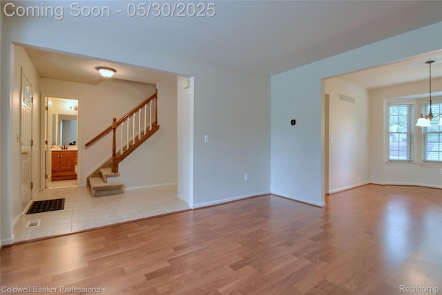 1468 N Morton Taylor Rd, Canton, MI 48187 - unfurnished living room featuring wood finished floors, stairs, baseboards, and a chandelier
