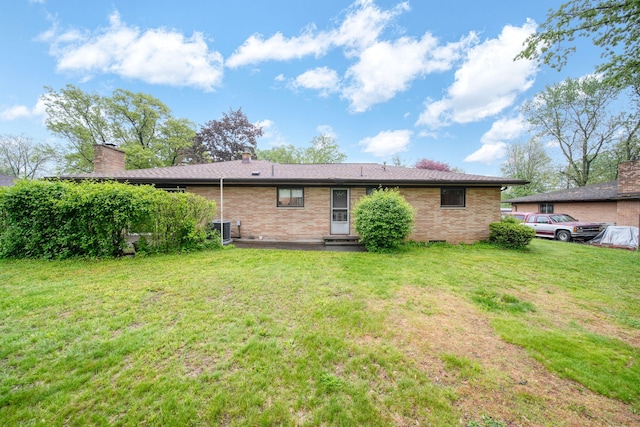 2074 Campbell Dr, Jackson, MI 49202 - rear view of house featuring central air condition unit, a yard, brick siding, and a chimney