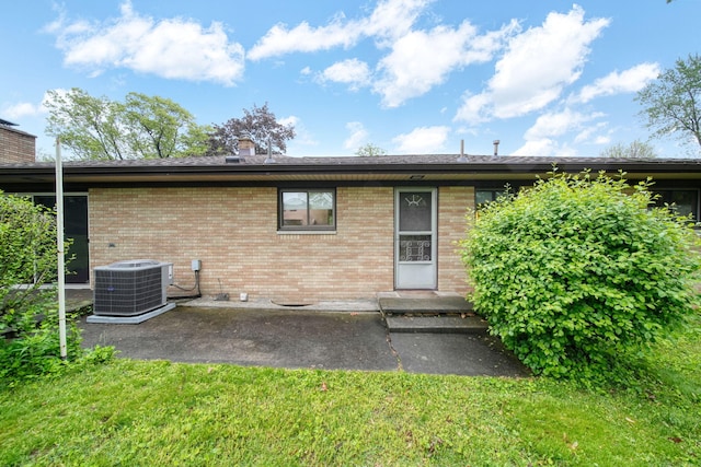 2074 Campbell Dr, Jackson, MI 49202 - rear view of house featuring cooling unit, brick siding, a patio, a chimney, and a yard