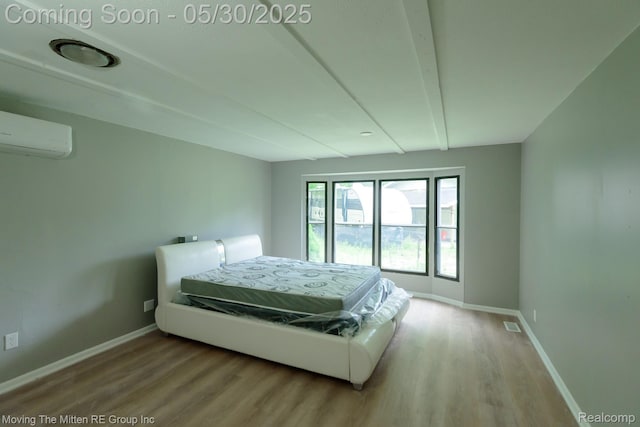 10531 Devils Lake Hwy, Addison, MI 49220 - bedroom featuring a wall unit AC, wood finished floors, and baseboards