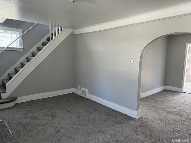 12632 E Canfield St, Detroit, MI 48215 - unfurnished living room with arched walkways, carpet flooring, stairway, and baseboards