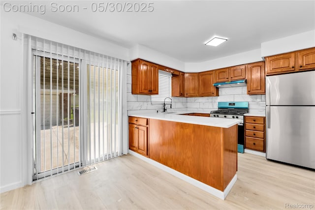 7278 Superior, Center Line, MI 48015 - kitchen featuring stainless steel appliances, under cabinet range hood, light wood-style floors, brown cabinetry, and decorative backsplash