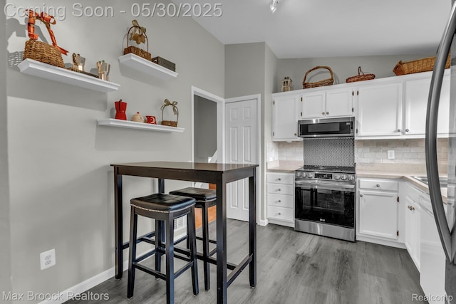 591 S Spinningwheel Ln, Bloomfield Hills, MI 48304 - kitchen with appliances with stainless steel finishes, wood finished floors, white cabinetry, backsplash, and light countertops