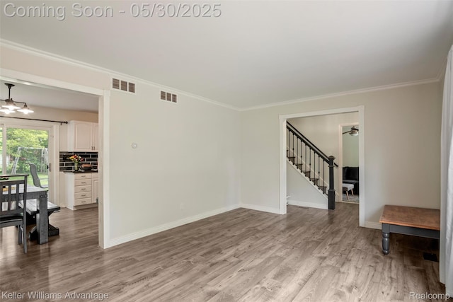 23355 Larkshire St, Farmington Hills, MI 48336 - empty room featuring light wood finished floors, baseboards, stairs, crown molding, and a chandelier