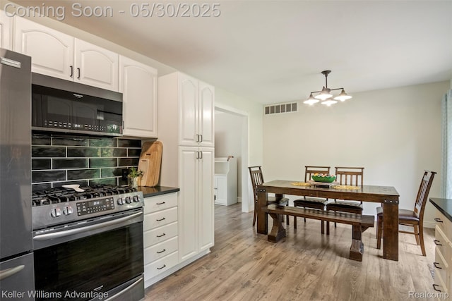 23355 Larkshire St, Farmington Hills, MI 48336 - kitchen featuring appliances with stainless steel finishes, dark countertops, decorative backsplash, white cabinets, and light wood-style flooring
