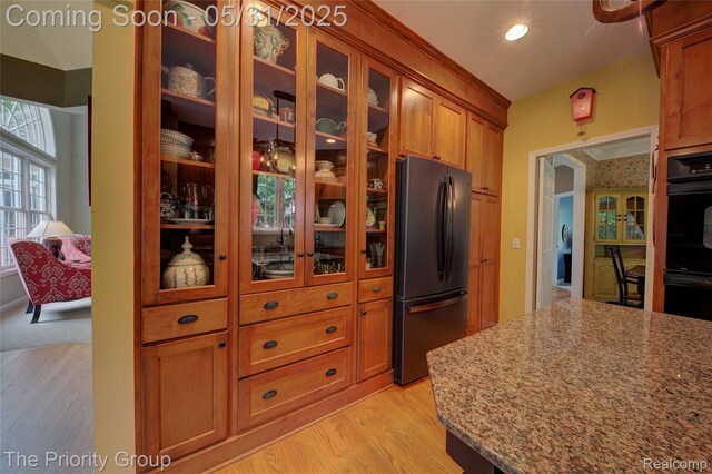 7730 Parkcrest Cir, Clarkston, MI 48348 - kitchen featuring black appliances, light wood finished floors, brown cabinets, light stone countertops, and glass insert cabinets
