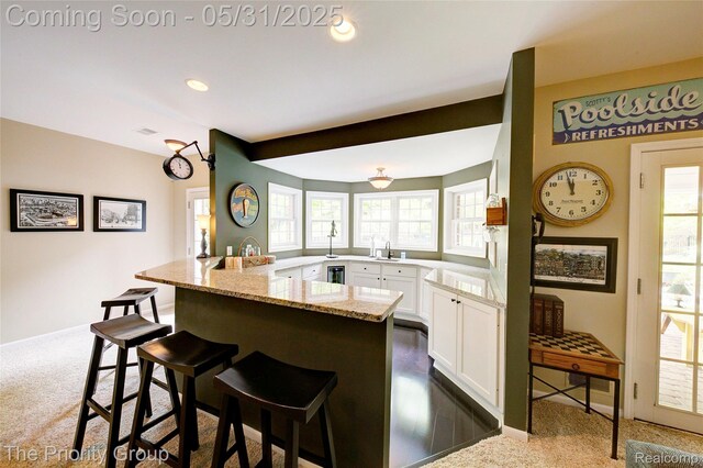 7730 Parkcrest Cir, Clarkston, MI 48348 - kitchen with a breakfast bar, dark carpet, light stone counters, white cabinets, and plenty of natural light