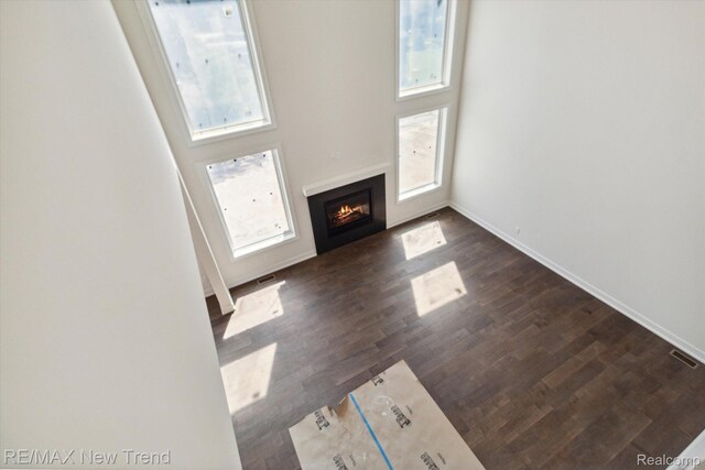 2911 Walsh Dr, Rochester Hills, MI 48309 - unfurnished living room with plenty of natural light, a lit fireplace, baseboards, and dark wood-style floors